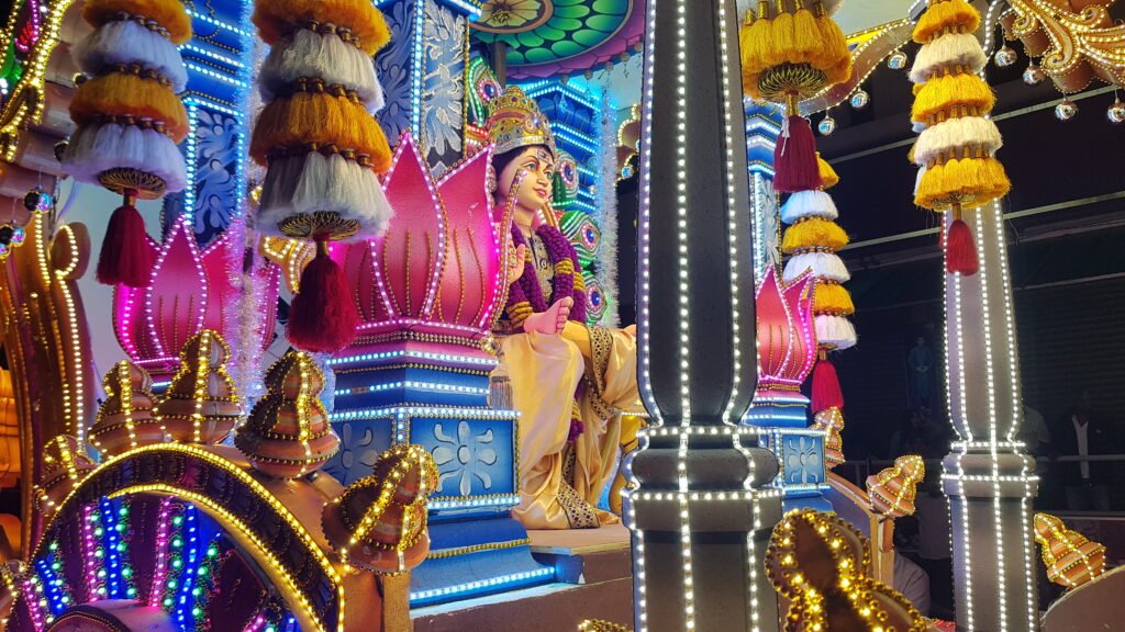 Devotee carrying a Ratham Kavadi featuring a statue of Lord Murugan during Thaipusam celebrations.