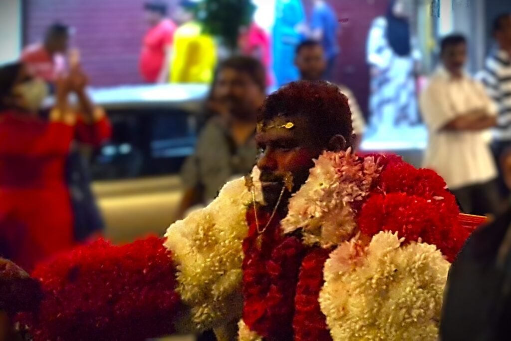 Thaipusam devotee in spiritual trance carrying kavadi with facial piercings.